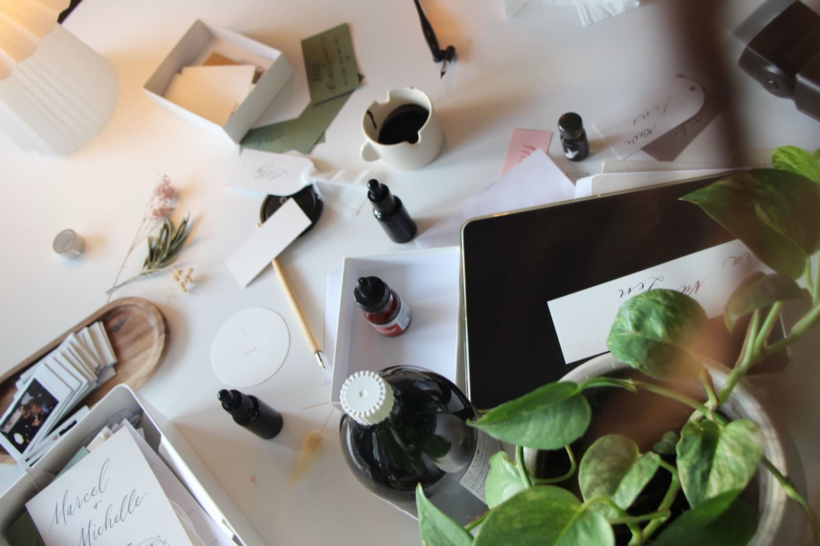 Arbeitstisch mit Tinten, Feder, Trockenblumen und kalligrafierter Papeterie