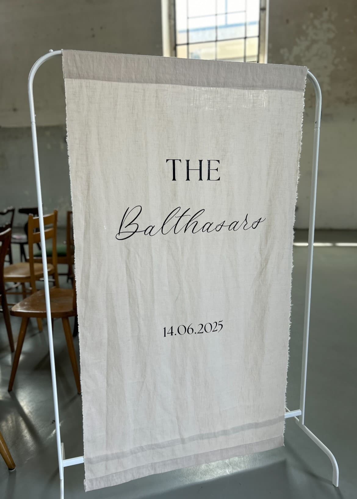 Leinen-Banner mit dem Kalligrafie-Schriftzug The Balthasars und Datum auf einem Ständer