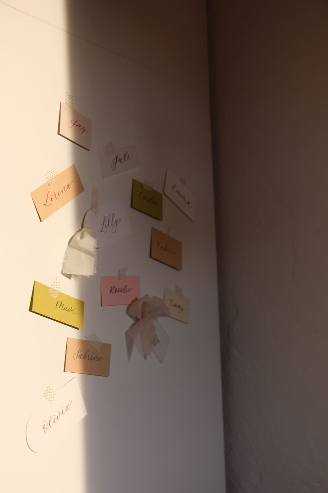 Mehrere farbige Namenskärtchen mit Kalligrafie an einer Wand arrangiert